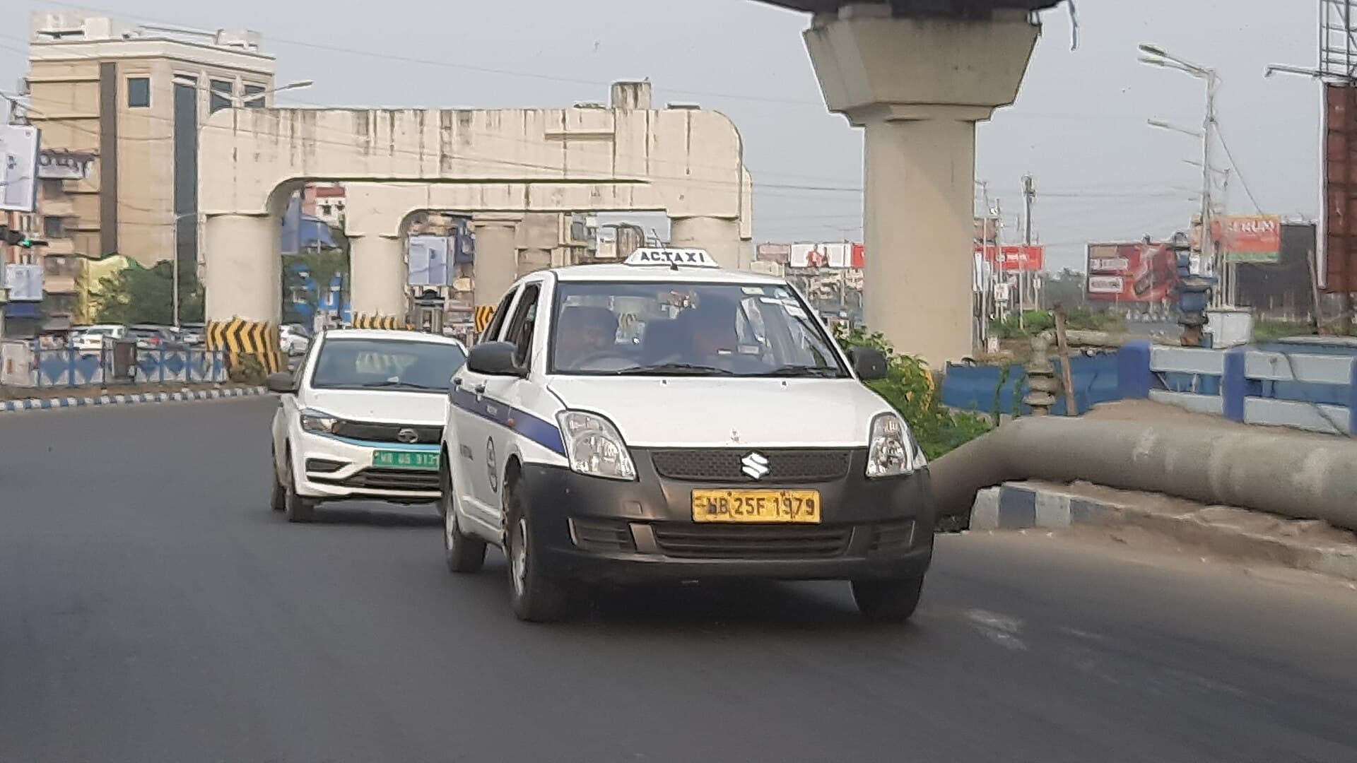 White air-conditioned Dzire taxi with a yellow commercial number plate on the Eastern Metropolitan Bypass, Kolkata