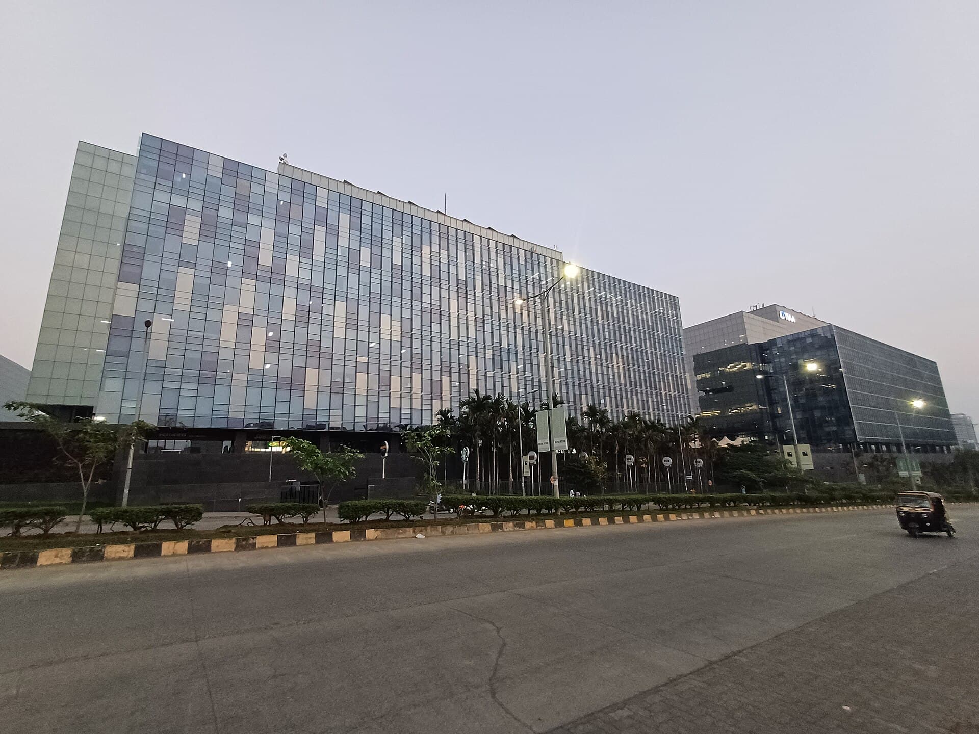Glass office buildings of World Trade Center Pune beside a wide road in Kharadi, Pune, at dusk