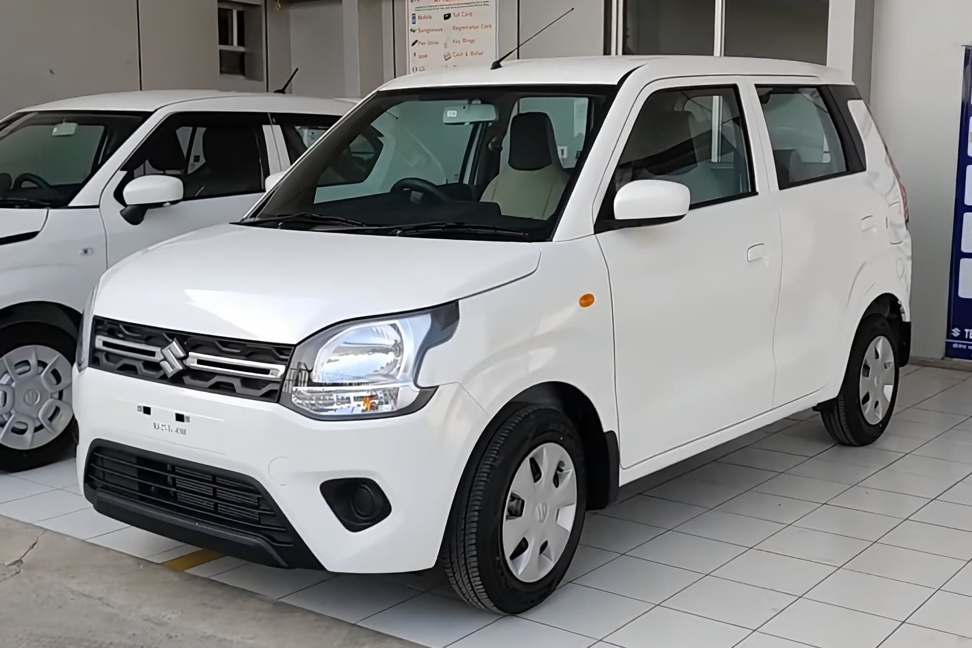 White Maruti Suzuki WagonR VXi hatchback, front three-quarter view, parked in a dealership showroom